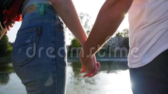 亲密的两个情人携手男人和女人牵着手站在池塘附近的细节轮廓视频的预览图