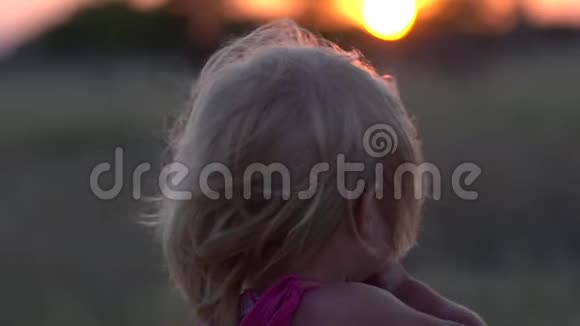 日落时在田野里的小女孩日落时的小女孩特写视频的预览图