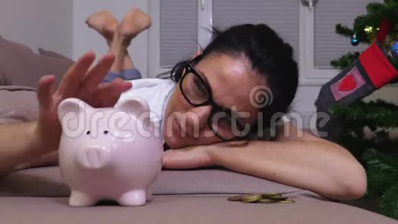 幸福的女人躺在靠近粉红色储蓄罐的沙发上视频的预览图