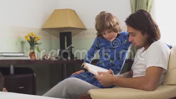 哥哥给弟弟读一本书穿着睡衣的兄弟们坐在椅子上讨论他们在读什么视频的预览图