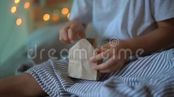 一个小男孩从一张挂在一张被点亮的床上的日历中打开礼物的慢镜头视频的预览图