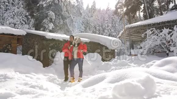 在清晨的阳光下幸福的一对夫妇在山上的冬天的小屋附近视频的预览图