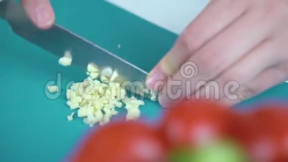 女性用手在切割板上切割大蒜前景是红辣椒视频的预览图