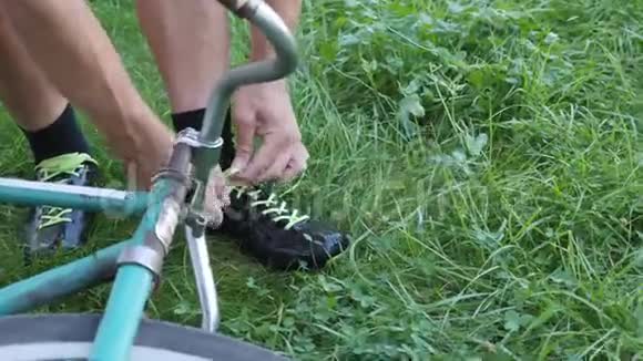 这段视频讲述了Cyclist在老式自行车附近的草地上系着他的自行车黑色鞋带视频的预览图
