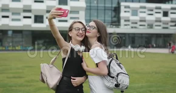 两个年轻女孩在智能手机上自拍自我肖像照片女性表现出积极的情绪视频的预览图