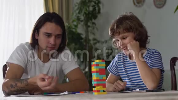 两个哥哥一个年轻一个成年人在桌子上玩游戏玩得很开心兄弟关系视频的预览图