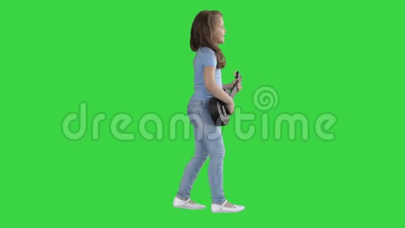 可爱的小女孩走着唱着在绿色的屏幕上弹着四弦琴色度键视频的预览图