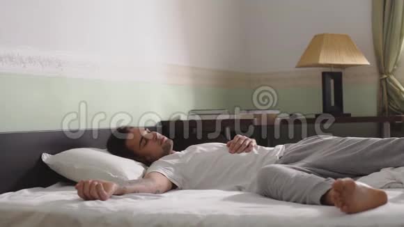 穿睡衣的年轻人躺在床上没有毯子视频的预览图