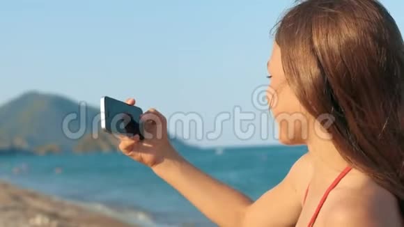 小女孩摆在手机摄像头前在海滨自拍视频的预览图