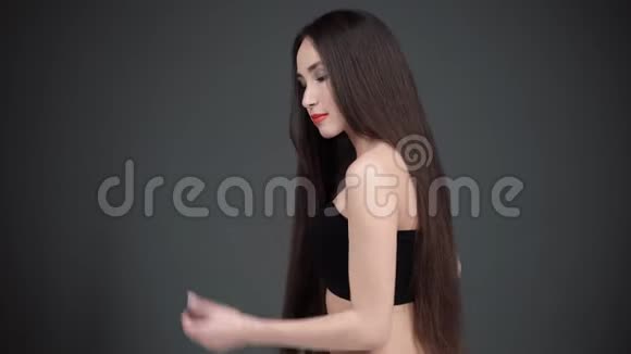 年轻女人用梳子梳头发有着豪华头发的女人在微笑深色背景视频的预览图