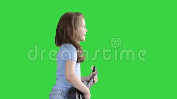 可爱的小女孩走路和唱歌同时在四弦琴上播放绿色屏幕Chroma键视频的预览图