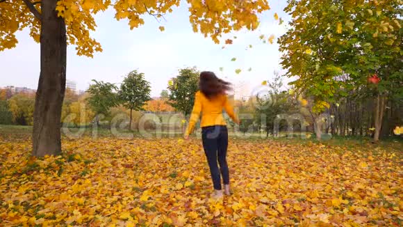 快乐的女人跳舞在飘落的黄叶中转身视频的预览图