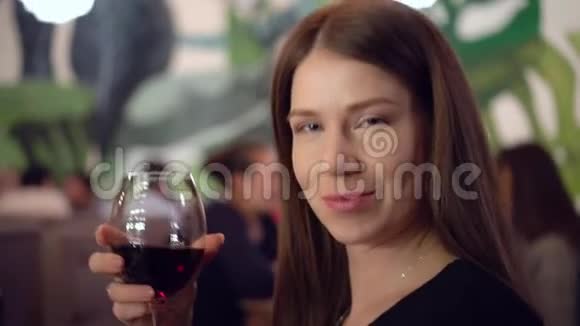 迷人的蓝眼睛棕色头发的女孩手里拿着一杯红酒视频的预览图