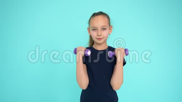 健身女孩举起哑铃训练手臂肌肉绿色背景视频的预览图