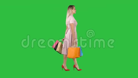 年轻女子带着购物袋看着绿色屏幕上的橱窗展示Chroma键视频的预览图