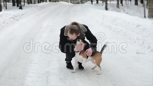快乐迷人的年轻人穿着黑色的外套在冬天和她的小猎犬一起散步友谊宠物和人类候选人视频的预览图