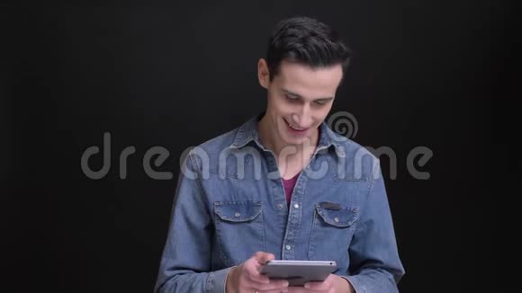 在平板电脑上打字的年轻白种人的特写肖像被分心看着背景的相机视频的预览图