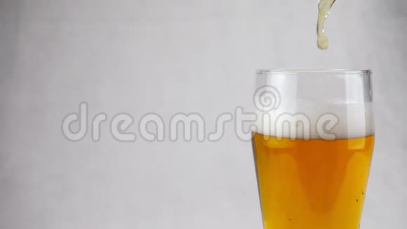 啤酒倒入白色背景的透明大玻璃杯中视频的预览图