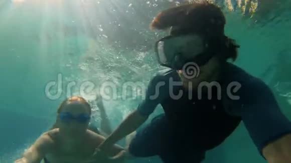 慢动作水下拍摄一对幸福的夫妇在游泳池里潜水健康的生活方式活跃的人视频的预览图