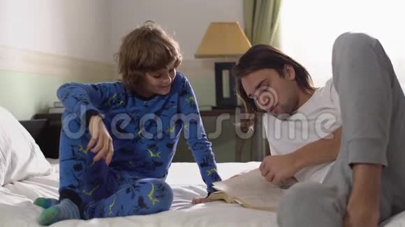 两个哥哥躺在床上哥哥为弟弟读一本书高五视频的预览图