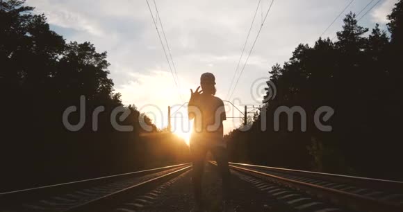 4k年轻人在铁路跑道旁靠太阳跳舞动作缓慢视频的预览图