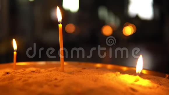 三支不同长度的燃烧蜡烛站在沙子里视频的预览图