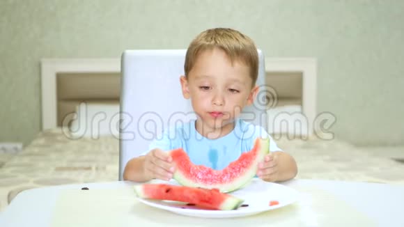孩子坐在桌子旁检查一块西瓜然后吃视频的预览图