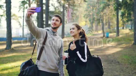 快乐的朋友运动的年轻人在公园户外练习后使用智能手机自拍男人和女人视频的预览图
