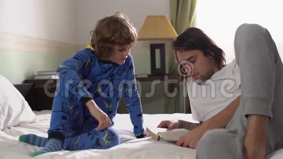 两个哥哥躺在床上哥哥为弟弟读了一本书他们表现得喜欢摄像竖起大拇指视频的预览图
