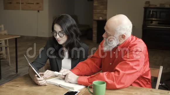 年轻女子与成熟男子看着屏幕上的数字平板电脑谈论它视频的预览图