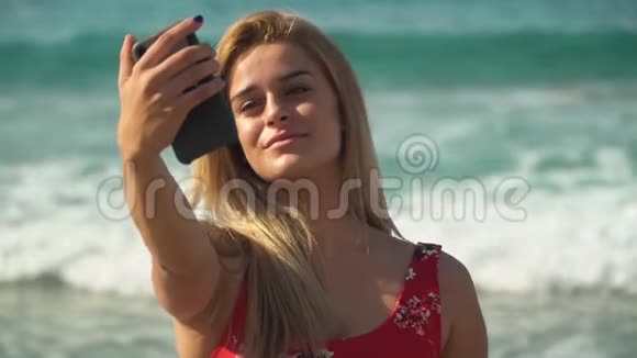 年轻漂亮的女孩在暑假的一片美丽的海洋背景上摆着自拍视频的预览图