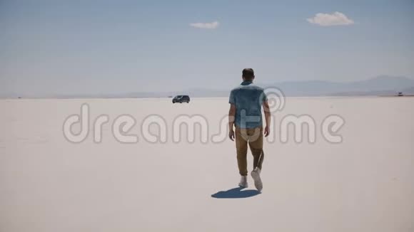 宽镜头镜头跟随年轻放松的游客在炎热的盐湖沙漠中走向小型货车视频的预览图