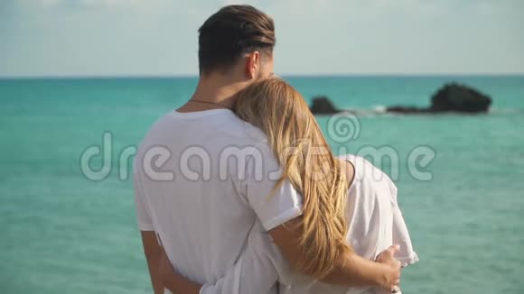 站在海边的一对年轻夫妇不得不近距离欣赏美丽的海景男人和女人温柔地拥抱在一起视频的预览图