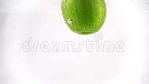 青苹果慢慢浸入水中慢动作录像白色背景下的孤立水果视频的预览图