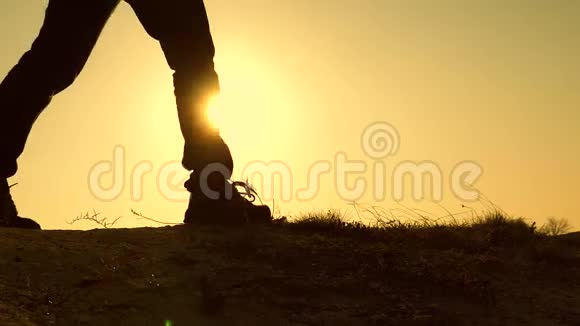 一个背着背包的旅行者的腿正在太阳升起的背景下沿着山脊行走旅行冒险视频的预览图