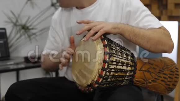 在家庭音乐工作室演奏djembe鼓乐器时手腕疼痛的音乐家视频的预览图