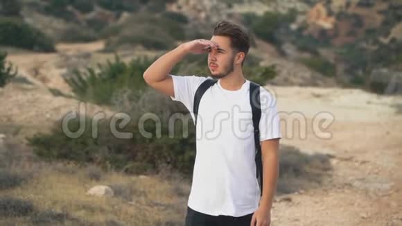 年轻有魅力的小伙子背着一个背包在风空的海滨沉思地眺望远方视频的预览图
