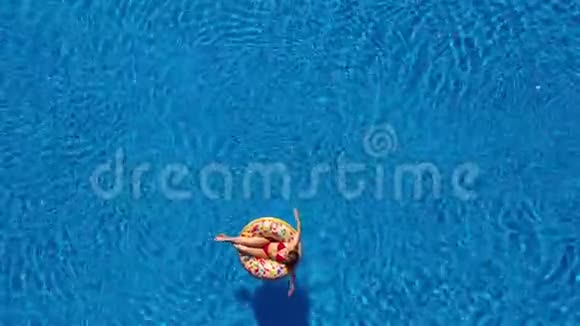 当女孩躺在甜甜圈泳池上时人在泳池里游泳视频的预览图