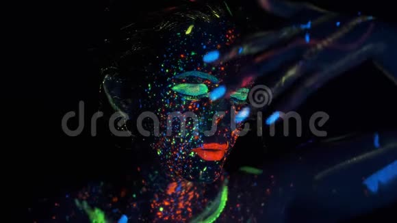 女孩在霓虹灯下的脸一个画着发光颜料的女孩的肖像视频的预览图
