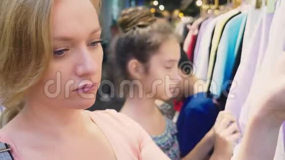 母亲和女儿在孩子们服装店里挑选新衣服视频的预览图