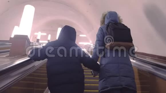 妈妈和儿子穿着冬天的衣服正在地铁隧道里上扶梯后景视频的预览图