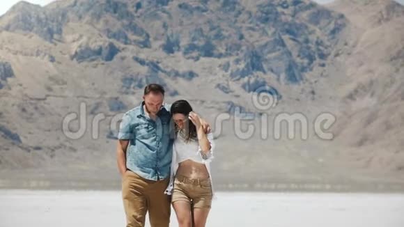 快乐成功的高加索浪漫夫妇在犹他州邦纳维尔的盐漠湖散步拥抱和愉快交谈视频的预览图