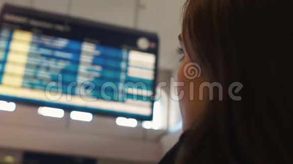女人看着机场展示板查看离港航班状态特写镜头视频的预览图