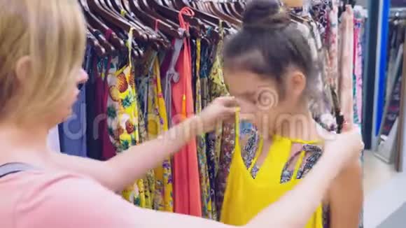 母亲和女儿在孩子们服装店里挑选新衣服视频的预览图