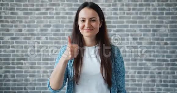 快乐学生的画像在砖墙的背景上竖起大拇指微笑视频的预览图