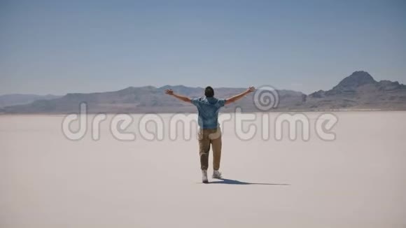 男人张开双臂在美丽的阳光明媚的盐湖里散步幸福的概念和生活的成功视频的预览图