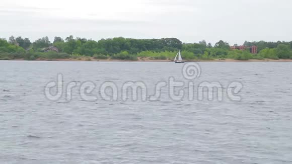 一艘白色的小帆船在一条宽阔的大河中间视频的预览图