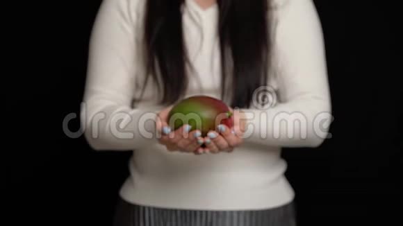 女人手里拿着芒果在黑色着芒果视频的预览图