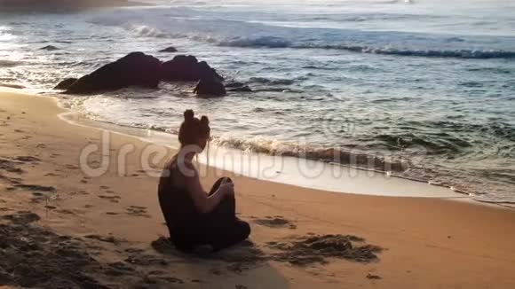 穿着黑色运动服的令人兴奋的女士坐在沙滩上视频的预览图