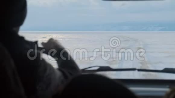 一个人在冰冻的湖面上驾驶汽车的剪影视频的预览图